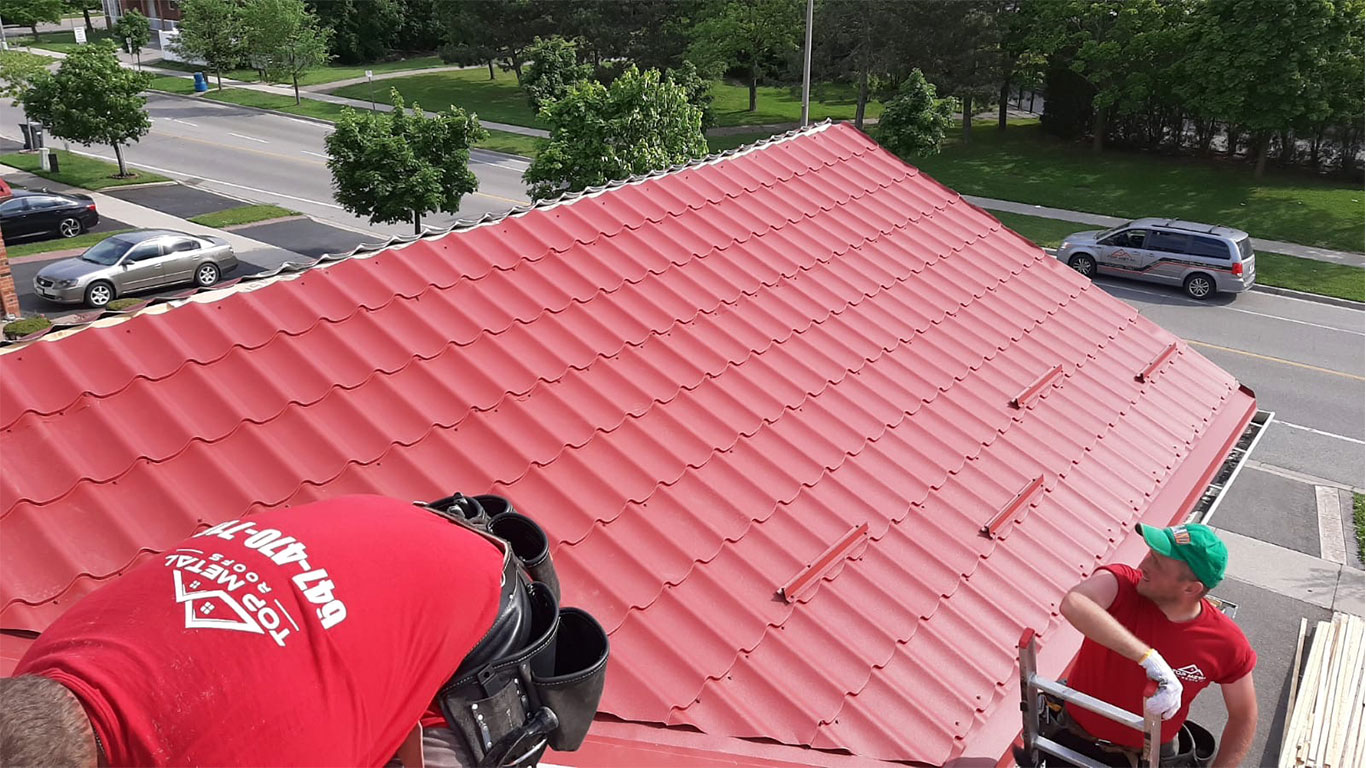 Metal roofing installers on a red metal roof.